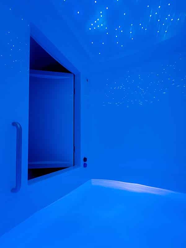 Empty full-height float room with warm saltwater pool and starry ceiling lights