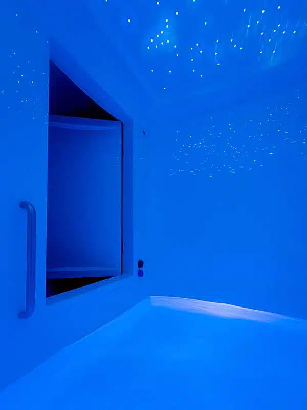 Empty full-height float room with warm saltwater pool and starry ceiling lights